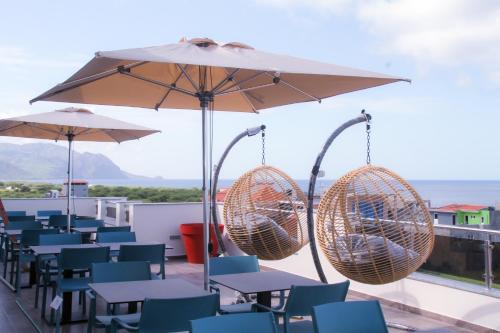 a patio with tables and chairs and an umbrella at Hotel Por Do Sol in Tarrafal