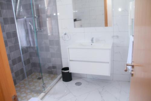 a bathroom with a shower and a sink and a mirror at Hotel Por Do Sol in Tarrafal