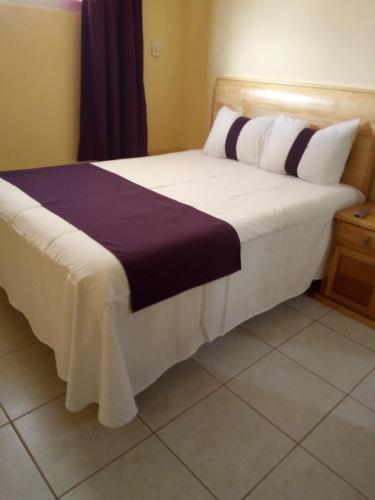 a bedroom with a large bed with purple and white pillows at Hotel Boutique Tonalli in San Martín de las Pirámides