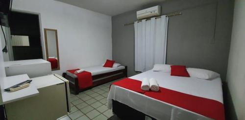 a hotel room with two beds and a mirror at Hotel Pousada Mar Azul in Tamandaré