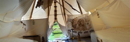 Cette chambre comprend 2 lits avec des rideaux blancs. dans l'établissement Tipi nature grand confort, à Gavarnie