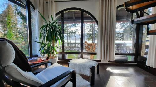 a living room with a chair and a table and windows at Spacious Apartment "Ana" on lake Sabljaci in Ogulin