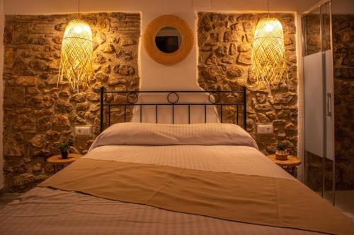 a bedroom with a bed with stone walls and lights at Knysna Boutique Rooms in Peniscola