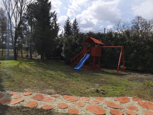 Őrségi Malom Panzió في Bajánsenye: ملعب مع زحليقة في حديقة