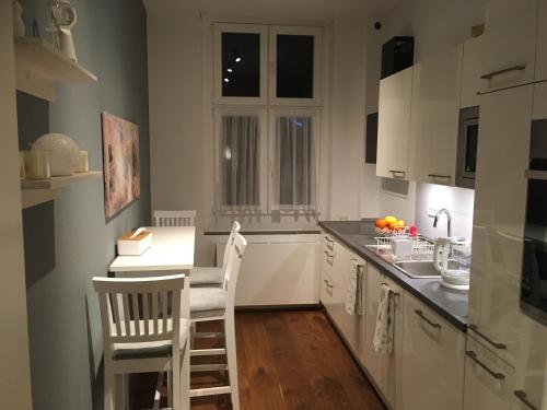 a kitchen with white cabinets and a table and chairs at City-Apartment Ohligs in Solingen