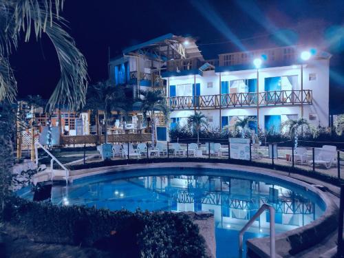 a swimming pool in front of a hotel at night at La Rivera Playa Palomino in Palomino