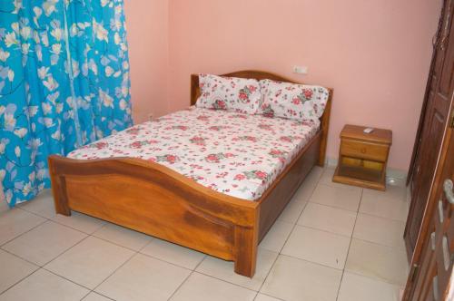 a small bedroom with a wooden bed and a night stand at RESIDENCE AMAR in Douala
