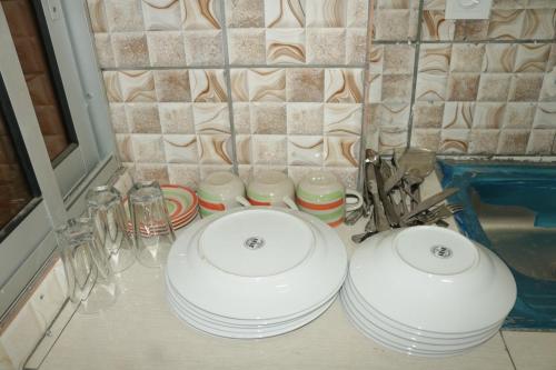 two white dishes sitting on a counter next to a sink at RESIDENCE AMAR in Douala