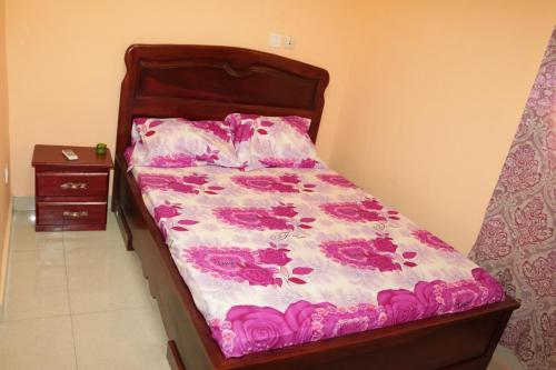 a small bed with a pink and white comforter at RESIDENCE AMAR in Douala