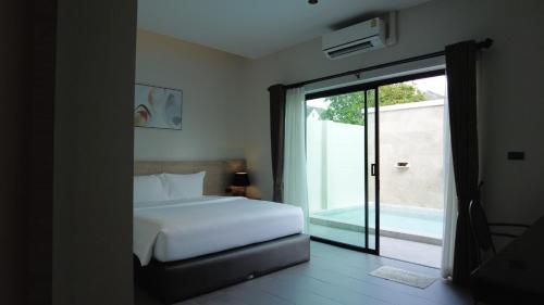 a bedroom with a bed and a sliding glass door at Toledo Pool Villa in Nakhon Si Thammarat