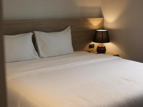 a large bed with white pillows and a lamp at Toledo Pool Villa in Nakhon Si Thammarat