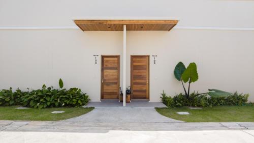 a white building with wooden doors and plants at Toledo Pool Villa in Nakhon Si Thammarat