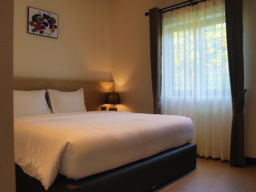 a bedroom with a large bed and a window at Toledo Pool Villa in Nakhon Si Thammarat