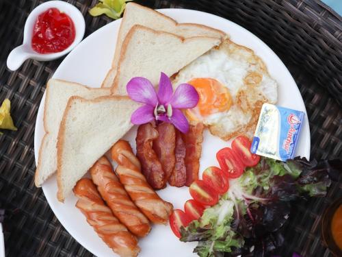 a plate of breakfast food with eggs sausage and toast at Toledo Pool Villa in Nakhon Si Thammarat