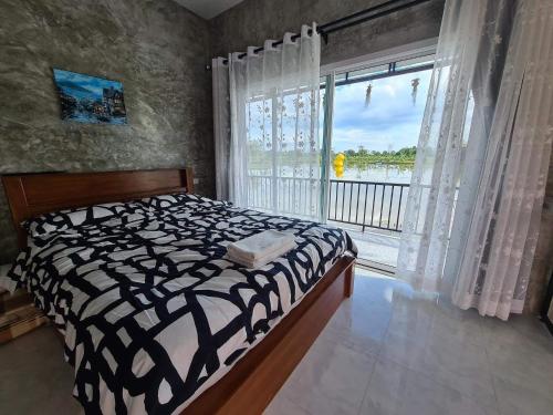 a bedroom with a bed and a large window at Eden House Resort in Nakhon Nayok