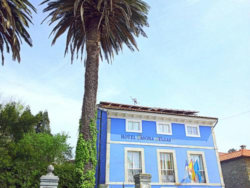 un edificio azul con una palmera delante de él en H Casona Selgas de Cudillero, en Cudillero