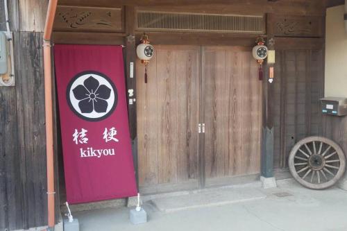une porte d'entrée d'un bâtiment avec un panneau kiwi sur celui-ci dans l'établissement 民泊 桔梗, à Awaji
