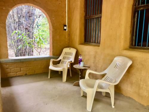 two chairs and a table in a room with a window at Kamp Kamouflage Kanha in Kānha