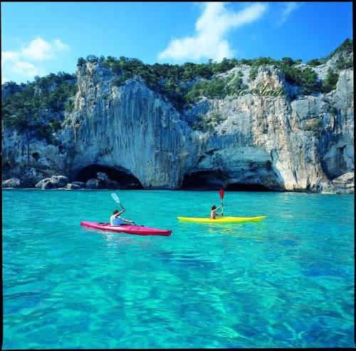 two people kayaking in the water in front of a cave at Bed and Breakfast Su Niu in Quartucciu