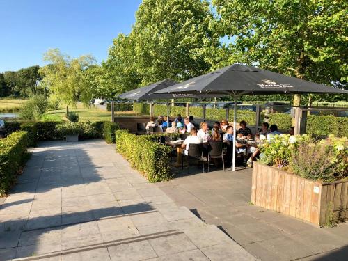 a group of people sitting at tables under an umbrella at Safaritent Mini Lodge in Kesteren
