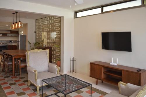 a living room with a table and a television on a wall at CASA LÁZARO- Hermosa casa familiar in Mérida