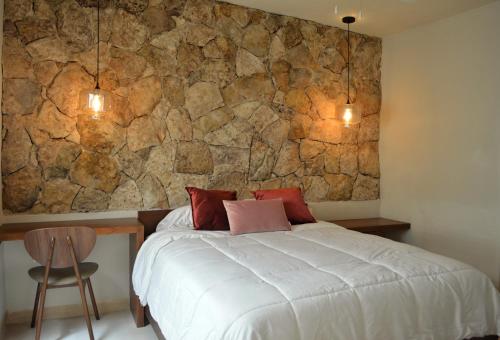 a bedroom with a bed and a stone wall at CASA LÁZARO- Hermosa casa familiar in Mérida