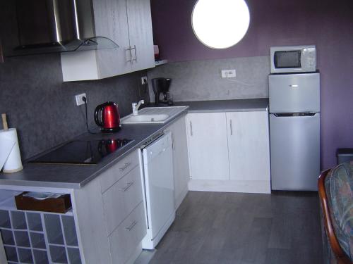 Elle comprend une petite cuisine avec des placards blancs et un réfrigérateur. dans l'établissement Gîte Paul et Rosalia, à Manneville-la-Raoult