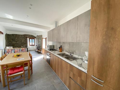 eine Küche mit einer Spüle, einem Tisch und einer Theke in der Unterkunft Independent Stone House with Lake View in Musso
