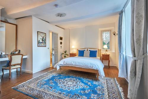 ein Schlafzimmer mit einem Bett und einem blauen Teppich in der Unterkunft Le Manoir des Doyens in Bayeux