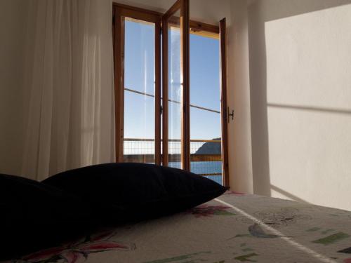 a pillow sitting on a bed in front of a window at M'illumino d'immenso - MONEGLIA APARTMENTS in Moneglia