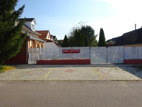 una cerca blanca con una puerta delante de una casa en Deluxe szoba, en Eger
