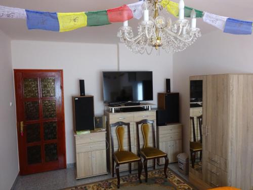 sala de estar con 2 sillas, TV y lámpara de araña en Deluxe szoba, en Eger