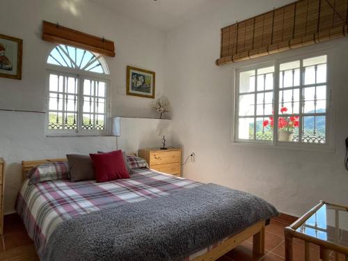 a bedroom with a bed and two windows at Alojamiento Rural El Paraíso del Chorro in El Chorro