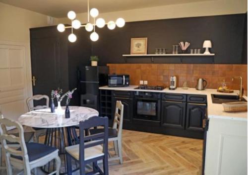 eine Küche mit einem Tisch und Stühlen sowie eine Küche mit einem Herd in der Unterkunft Maison d'hôtes La Bella Casa in Villette-dʼAnthon