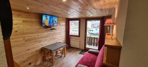 een kamer met een houten muur en een tv. bij Le Bois Joli in Saint-Pierre-de-Chartreuse