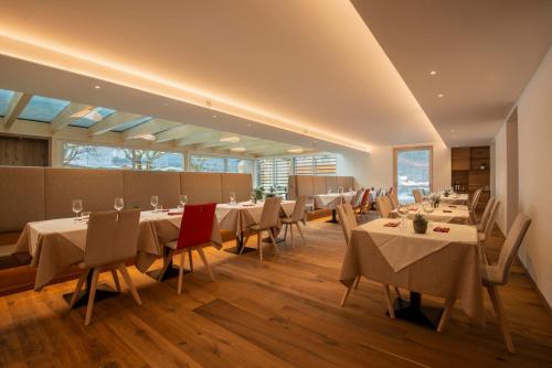 una sala da pranzo con tavoli, sedie e finestre di Residence Hotel Eden - Family & Wellness Resort ad Andalo