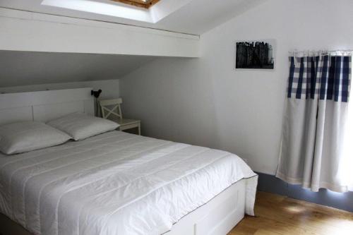 1 dormitorio con cama blanca y ventana en Villa avec piscine 12 personnes #0606 en Capbreton