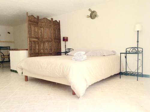 een slaapkamer met een wit bed en een houten deur bij Les flamants roses in Roussillon