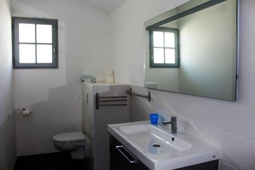 Baño blanco con lavabo y espejo en Villa avec piscine 12 personnes #0606 en Capbreton