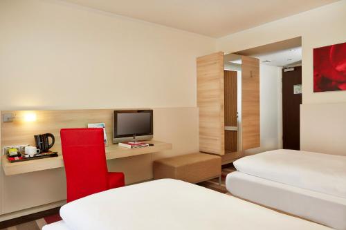 a hotel room with two beds and a television at H+ Hotel Bad Soden in Bad Soden am Taunus