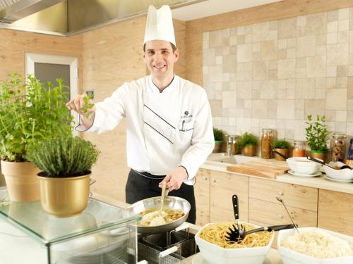 a chef standing in a kitchen preparing food at Wellness Hotel Apollo – Terme & Wellness LifeClass in Portorož