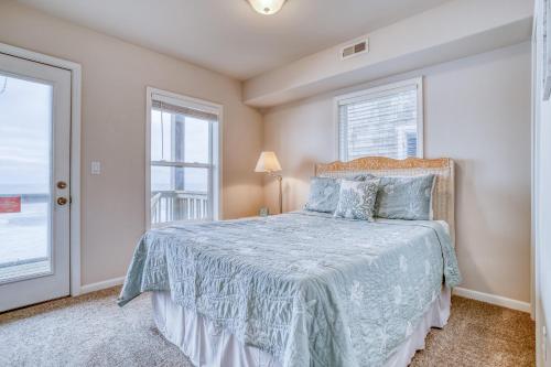 a bedroom with a bed with a blue comforter and two windows at SeaLaVie in Depoe Bay