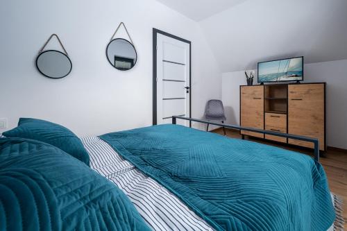 a bedroom with a bed with a blue blanket and a dresser at Chłapowska Przystań in Władysławowo