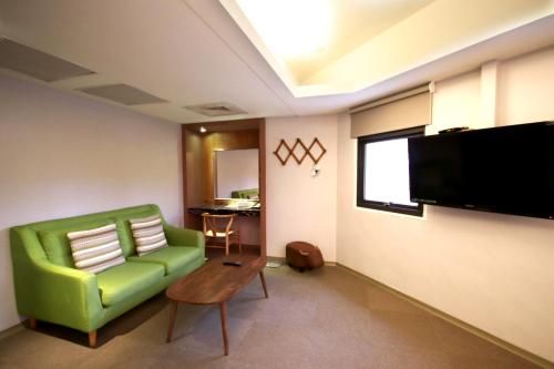 a living room with a green couch and a flat screen tv at Meci Hotel in Hualien City