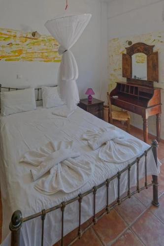 a bedroom with a bed with white sheets and a piano at PANORAMA in Pitsidia
