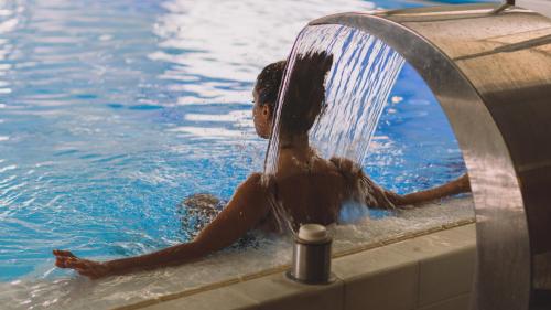 a girl is in the water in a swimming pool at Hotel Terme Milano in Abano Terme