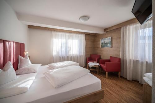a hotel room with two beds and a red chair at Hotel Plan Murin in La Valle