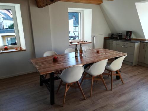 uma cozinha com uma mesa de madeira e cadeiras brancas em Präsenzhof Lay em Lay