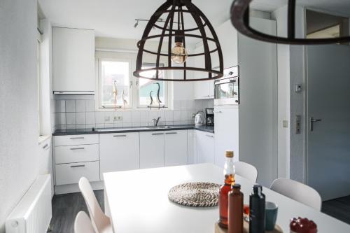 a kitchen with white cabinets and a chandelier at Vakantiewoning 114 in villapark de oesterbaai in Wemeldinge