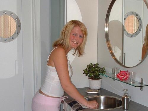 kobieta stojąca przed umywalką w łazience w obiekcie Two-Bedroom Holiday home in Kalvåg w mieście Kalvåg